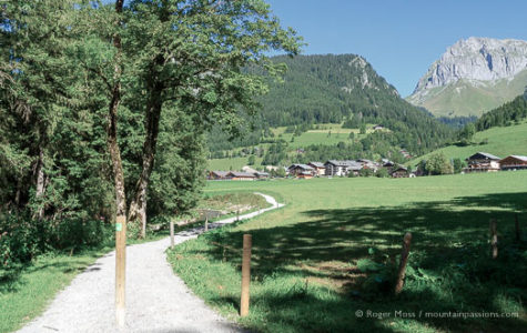 Wide view of cycle and footpath with mountains and village of La Chapelle d'Abondance in distance