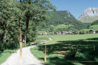 Wide view of cycle and footpath with mountains and village of La Chapelle d'Abondance in distance