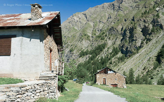 Mountain track between stone chalets, with steep-sided valley in Massif du Parpaillon, French Alps