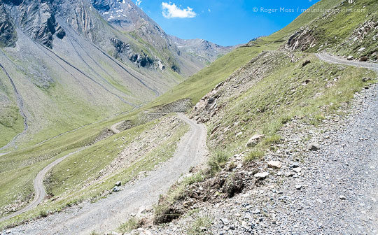 Wide view of unsurfaced mountain track with hairpin bends above steep-sided valley