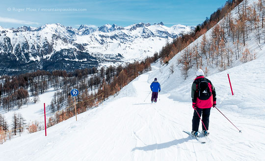 Two skiers on cruising piste at Vars, French Alps