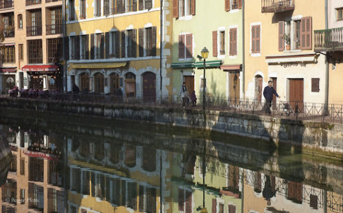 The vibrant pastel colours of the Italianate façades reflected in the calm waters of the canal, Annecy