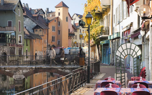 The quayside restaurant terraces look inviting, whether sunlit or illuminated at nightfall, Annecy