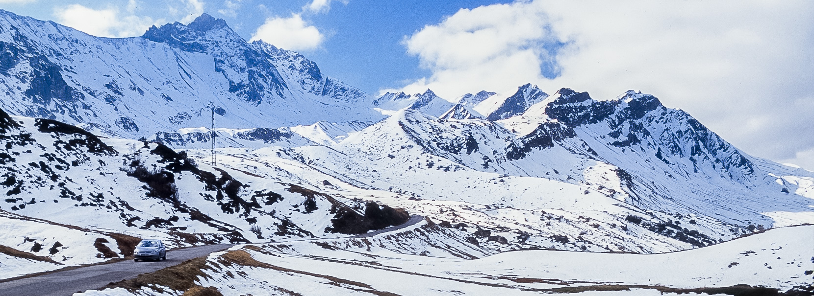 Wide view of Route des Grandes Alpes among snow-covered mountains