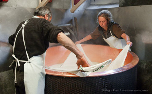 Jean-Pierre Blanc and assistant using muslin cloth to remove cheese from copper vessel while making Beaufort cheese.