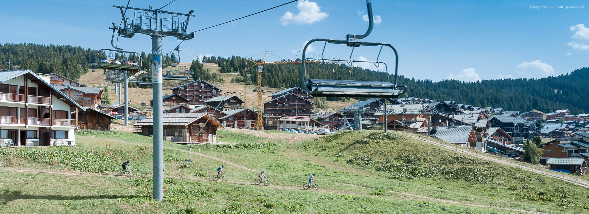 Wide view from chairlift of Les Saisies village with mountain-bikers