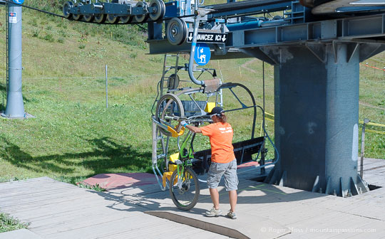Lift operator loading mountain bike onto chairlift at Les Saisies