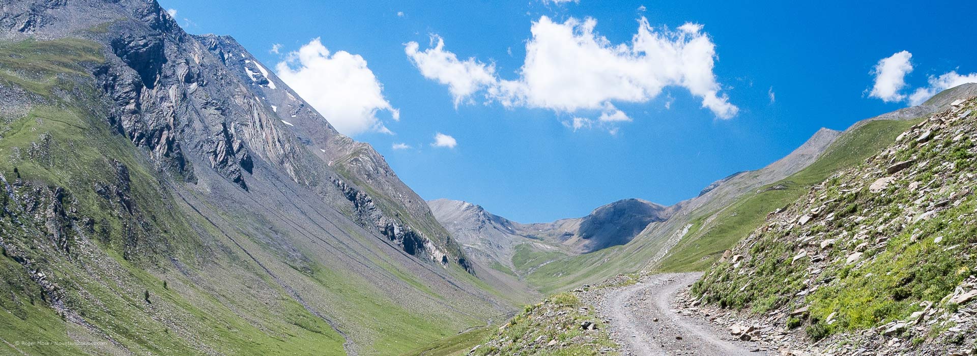 Wide view of mountain track climbing above wild valley