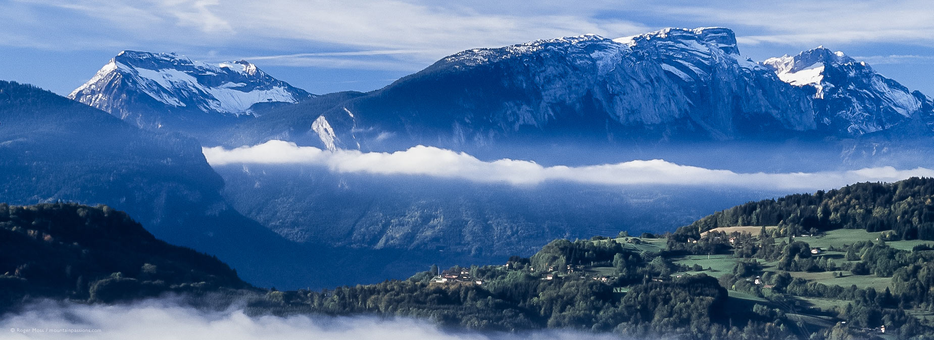 Wide overview of mountain landscape with morning mist from Route des Grandes Alpes above Tanninges, French Alps.