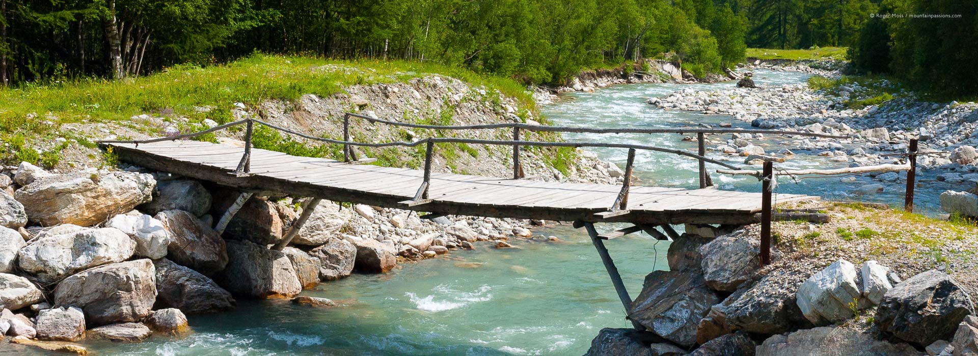 View of rustic wooden footbridge over mountain stream