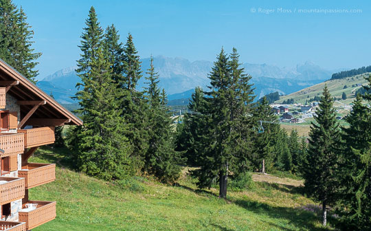 High view of village and mountains through trees from ski apartments in summer