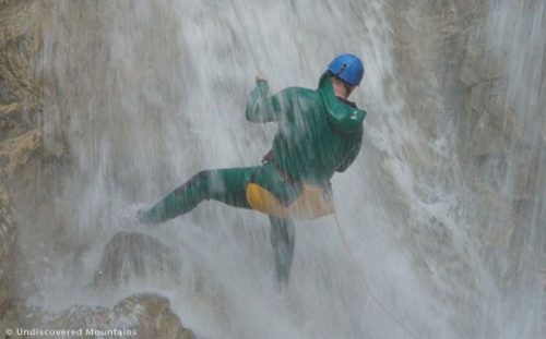 Abseiling under a waterfall, canyoning in the southern French Alps.