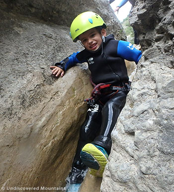 Small boy canyoning wearing all essential equipment.