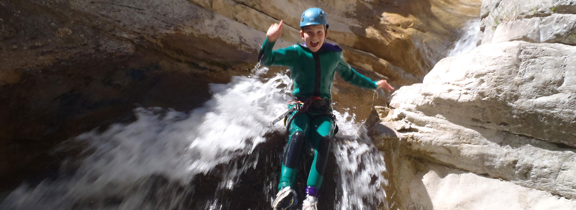 Canyoning in the southern French Alps - boy jumps over a waterfall.
