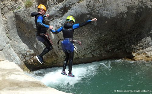 Canyoning couple jumping into pool, southern French Alps.