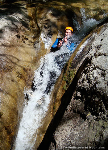 Sliding down a natural water toboggan while canyoning in the southern French Alps.