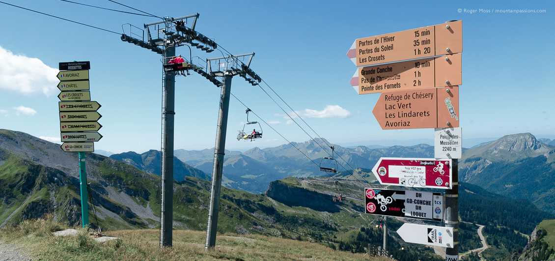 Mountain bikers on chairlift, with trail and footpath signage