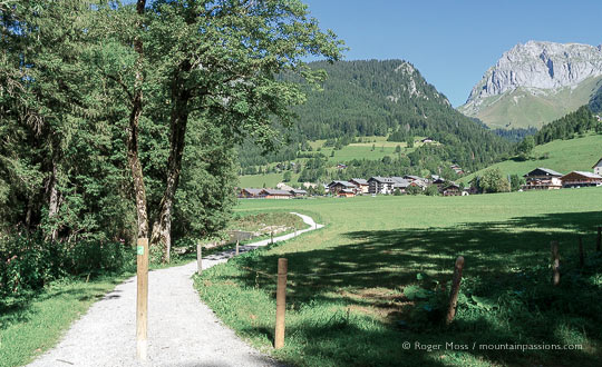 Wide view of cycle and footpath with mountains and village of La Chapelle d'Abondance in distance