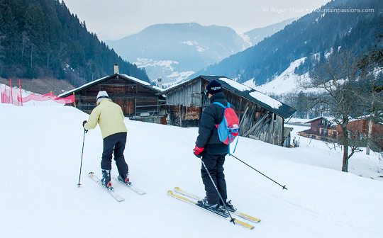 Skiers passing mountain chalets at Areches Beaufort, French Alps.