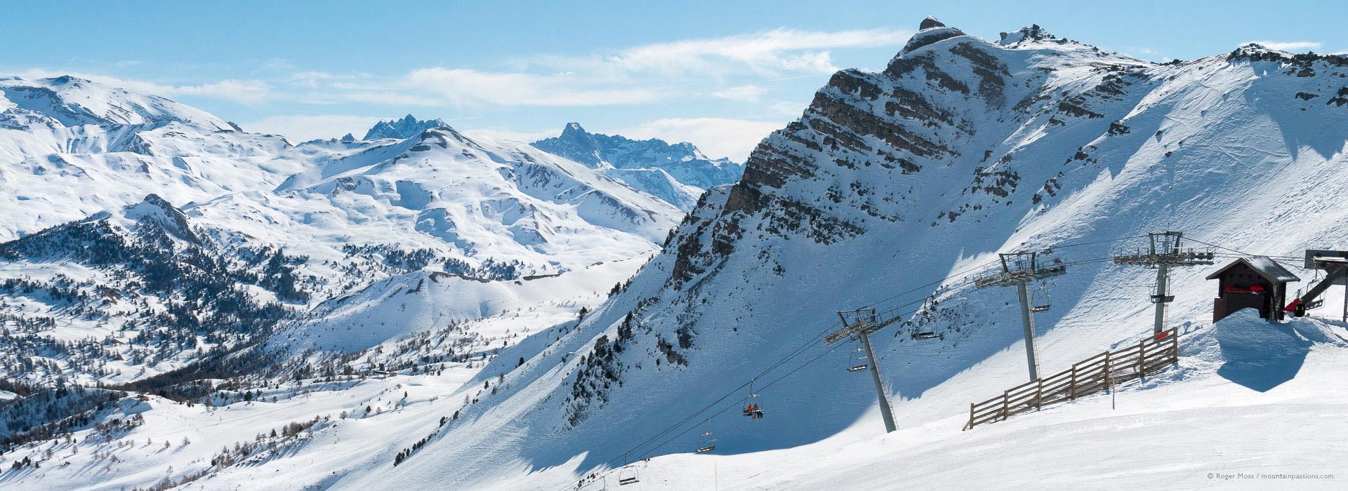 High view of snow-covered mountains with ski lift in foreground above Vars
