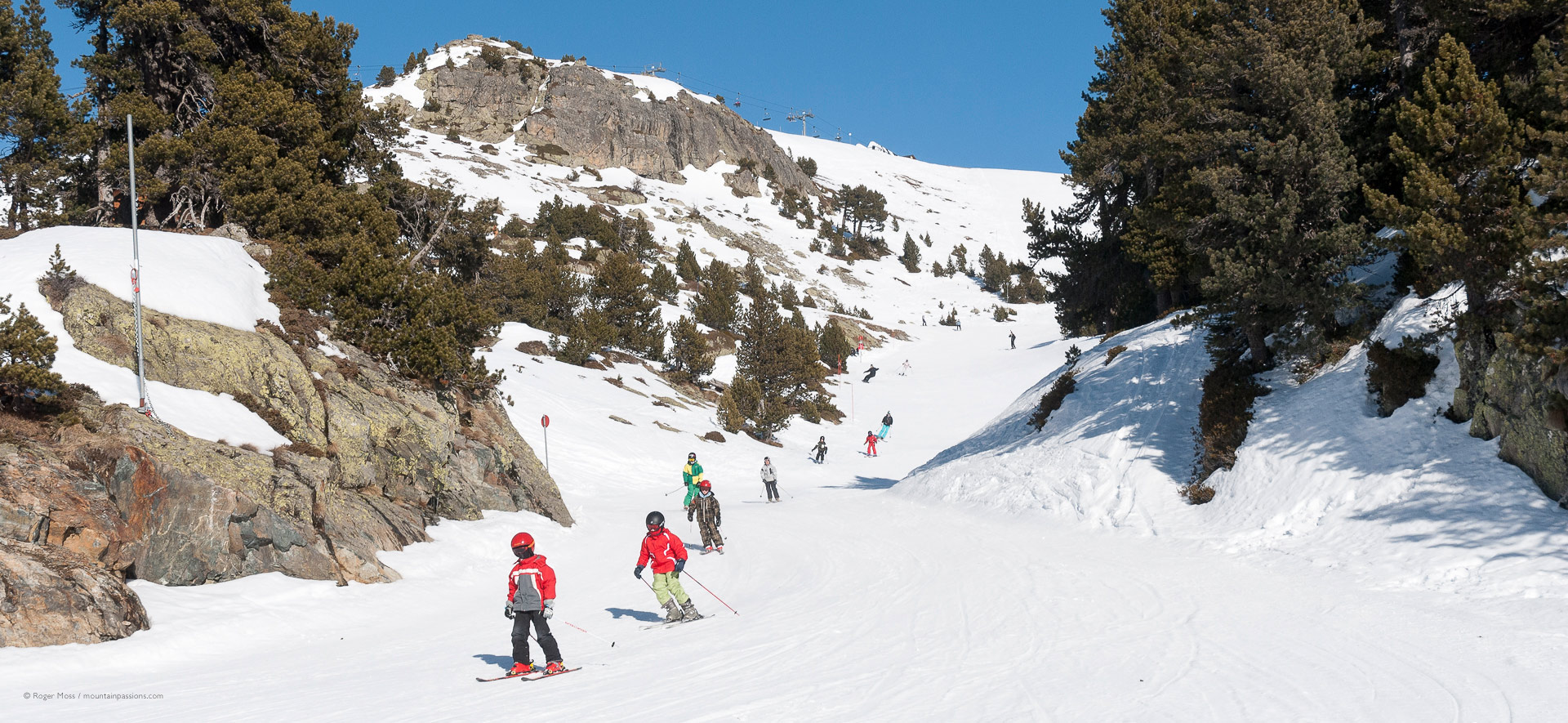 Group of children skiing in bright sunshine at Chamrousse.