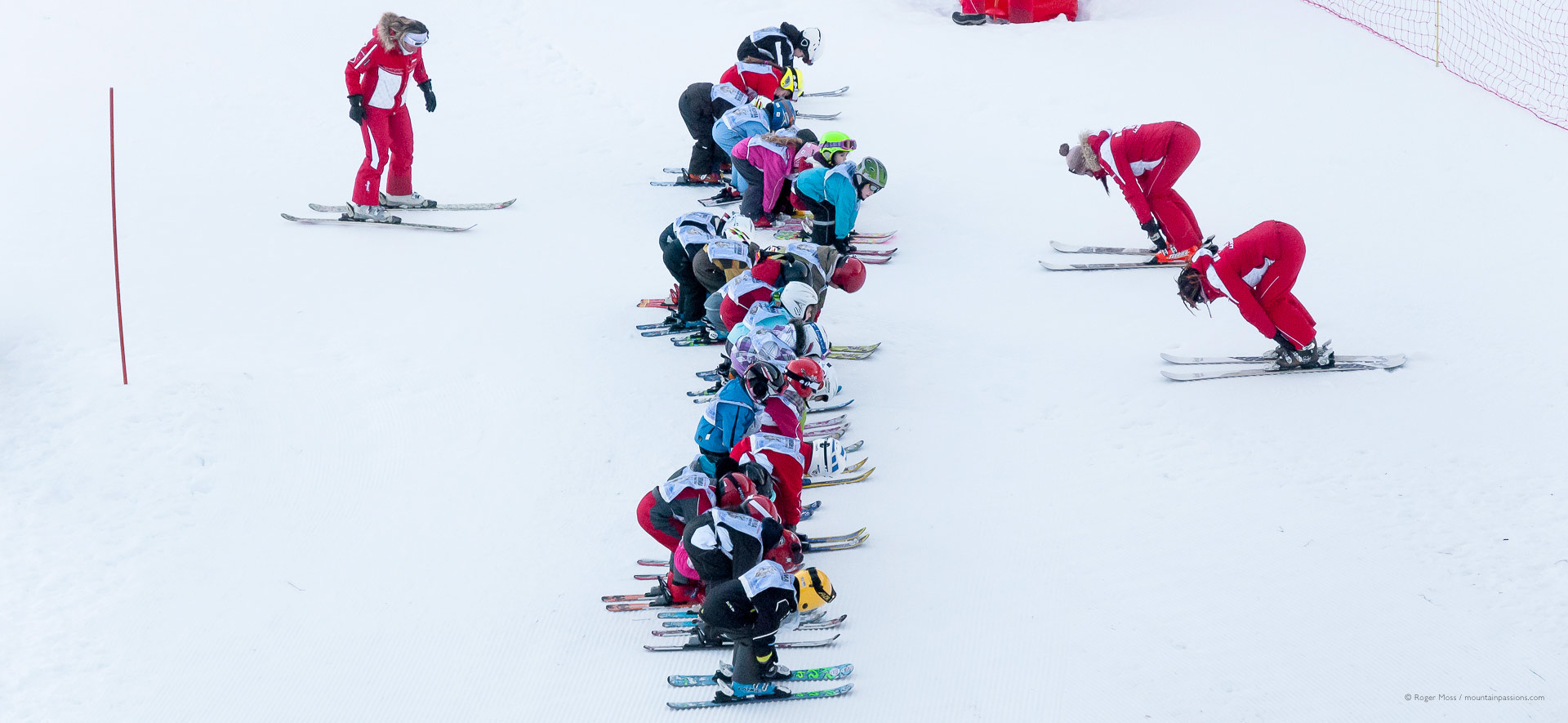 Bird's-eye view of ski instructors teaching children on the snow.