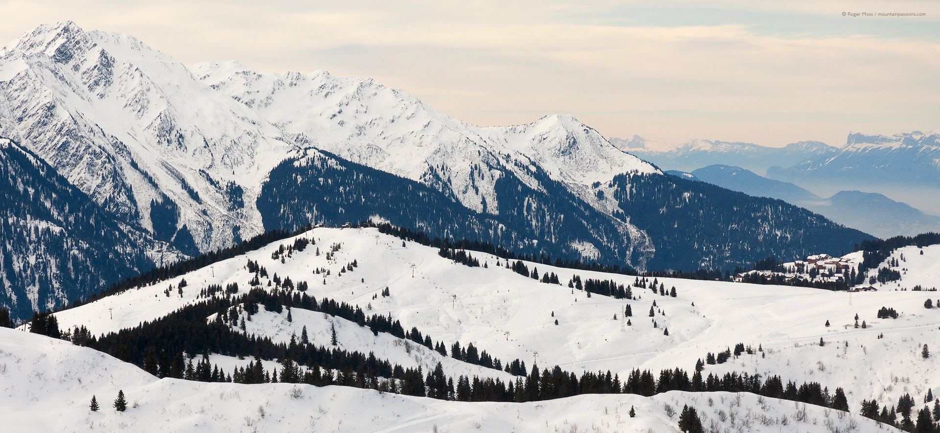 Wide view of Espace Diamant ski area above Crest Voland in soft early morning light.