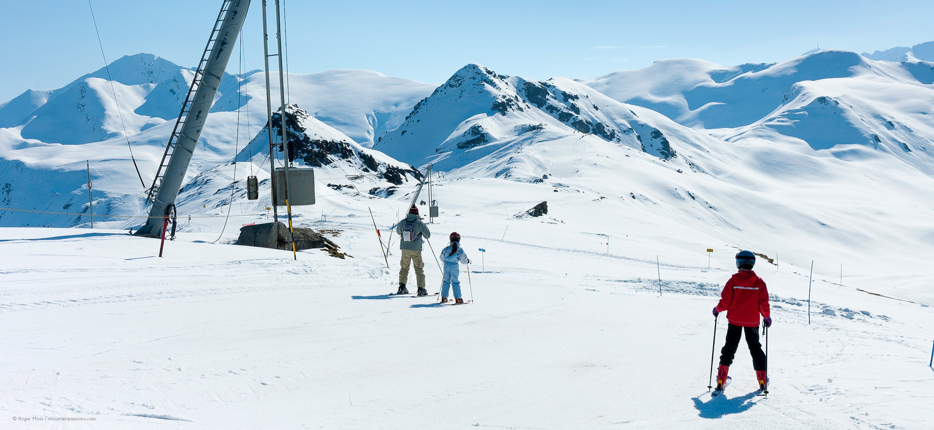 Family skiers beside drag-lift with wide mountain scenery