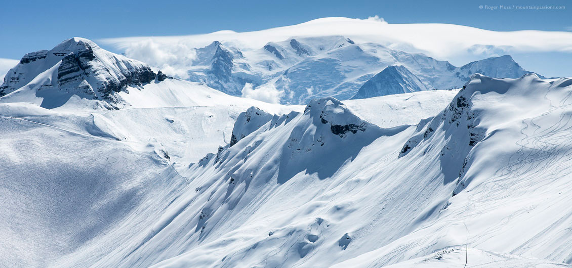 Wide view of snow-covered mountains with ski pistes