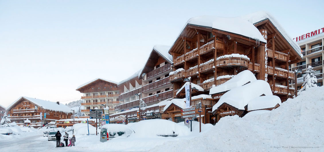 Family beside snow-covered hotels in ski village