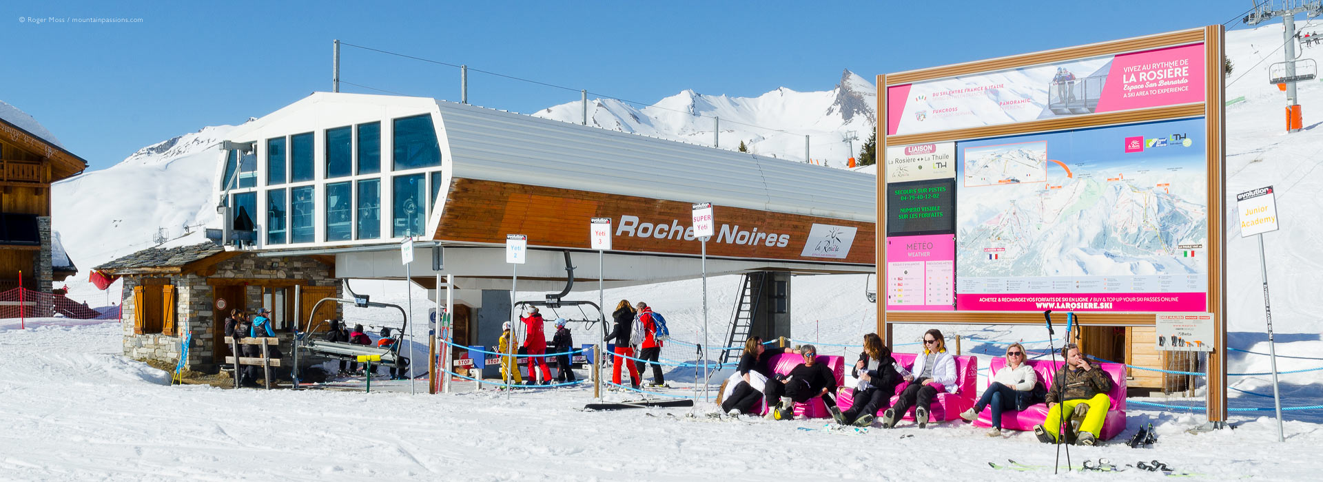 Skiers relaxing around high-speed chair lift at La Rosiere, French Alps