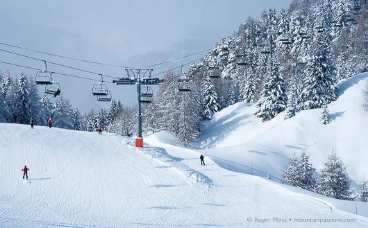 Forested pistes, chairlift and skiers, La Plagne