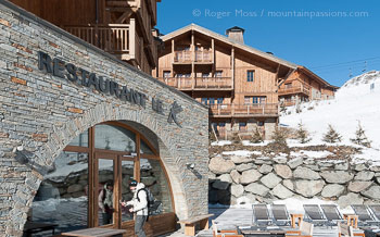 Skier entering mountain hotel restaurant with chalets at Les Menuires.