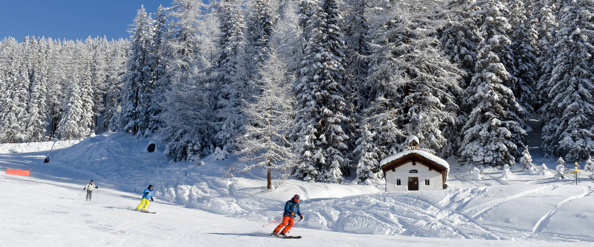 Skiers passing mountain chalet beside piste at Sainte Foy Tarentaise, French Alps.