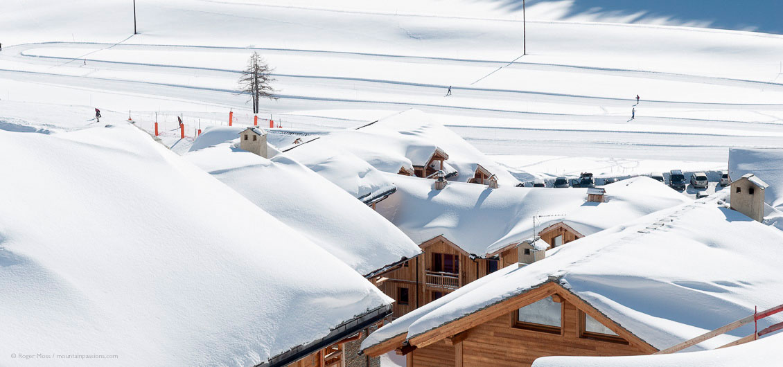 View across snow-covered rooftops to skiers on pistes