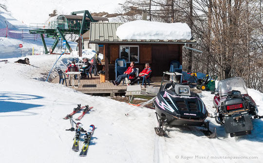 Small mountain bar with skiers and snowmobiles