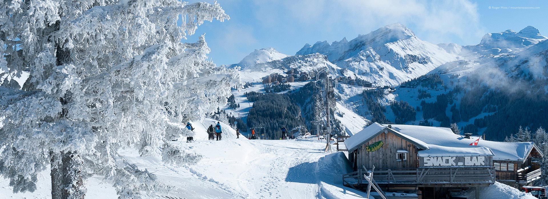 Wide view of skiers amid snowy landscapes.