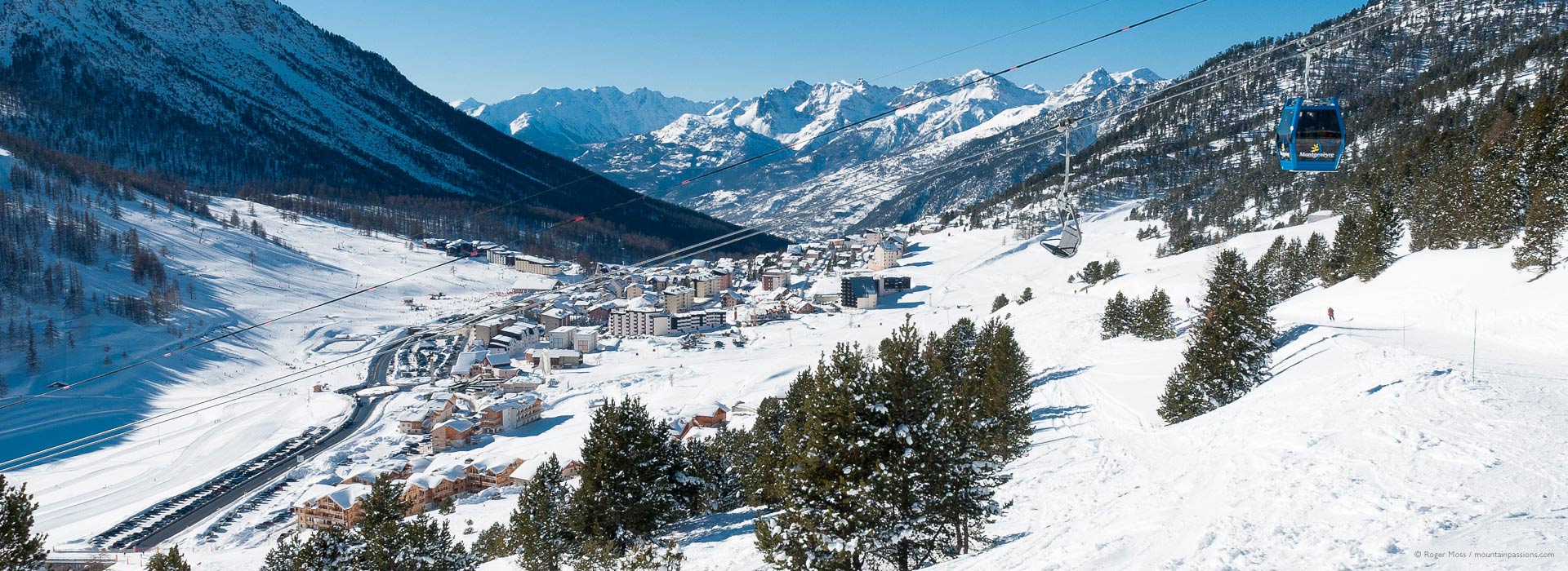 Wide view from chairlift of ski village, valley and mountains at Montgenevre.