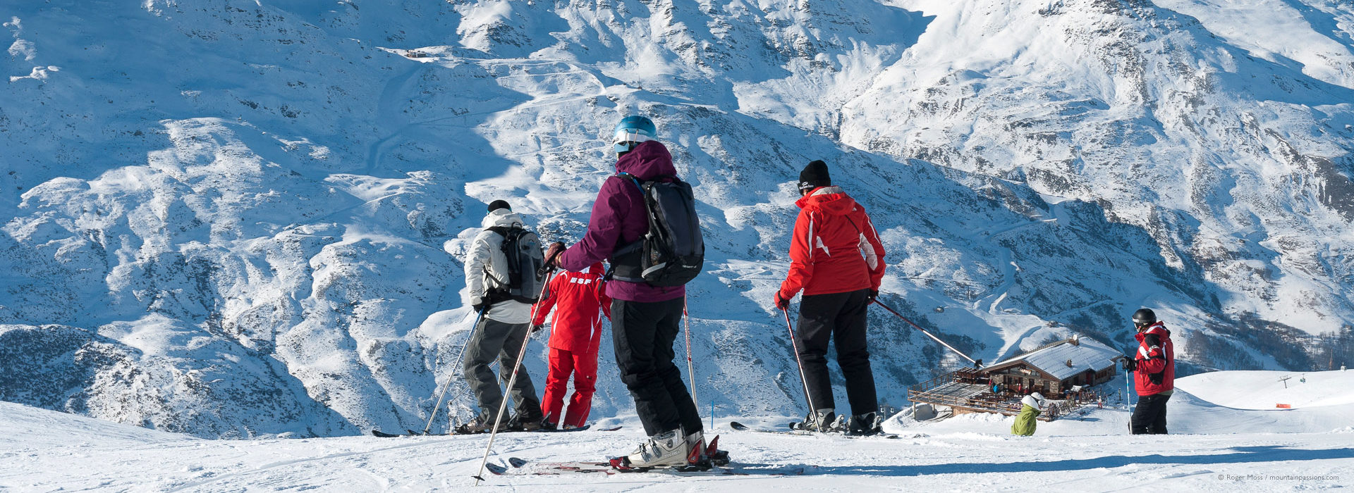 Group of skiers above mountain restaurant with snowy background.