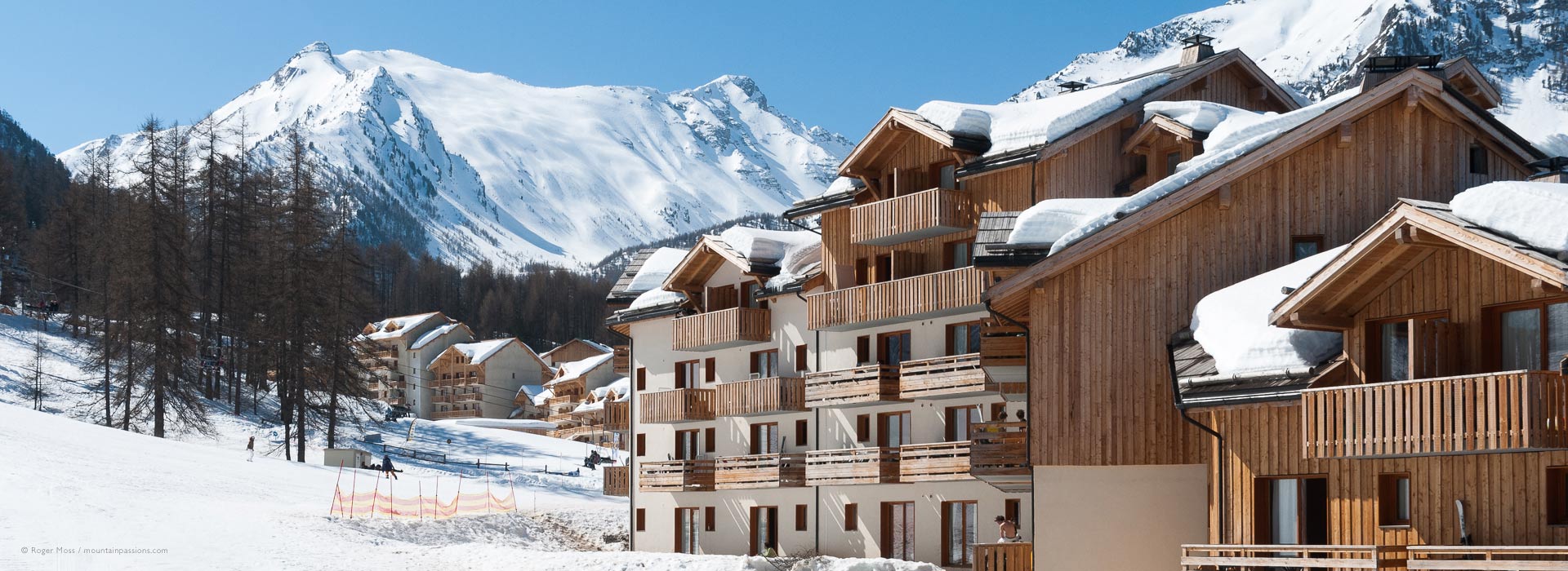 View of ski apartments with snow-covered roofs and mountain background at Les Orres