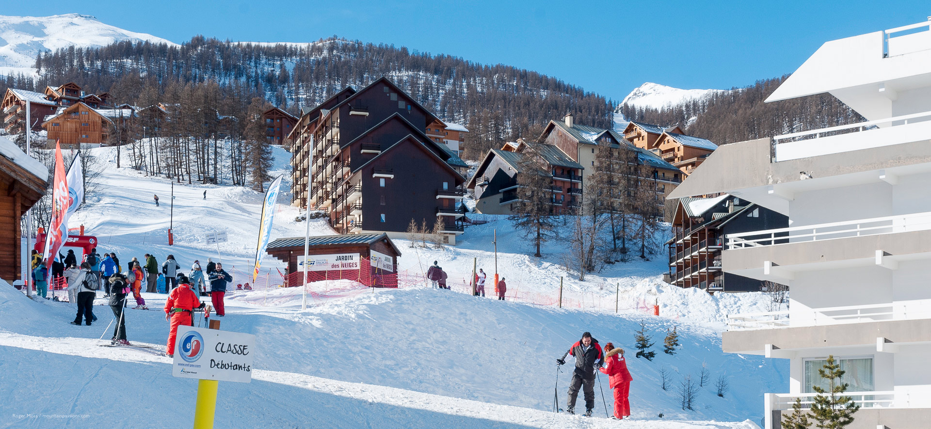 Novice skiers meeting at ski school area, with slopeside apartments in background