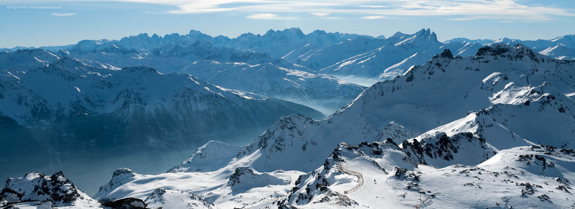 Vast mountain landscape with distant skier descending from Val Thorens to Orelle.