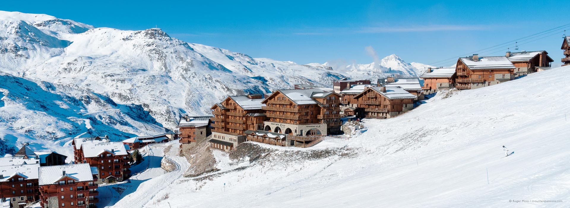 View of chalets at Les Menuires ski resort with snow-covered mountainside, 3 Valleys, French Alps.