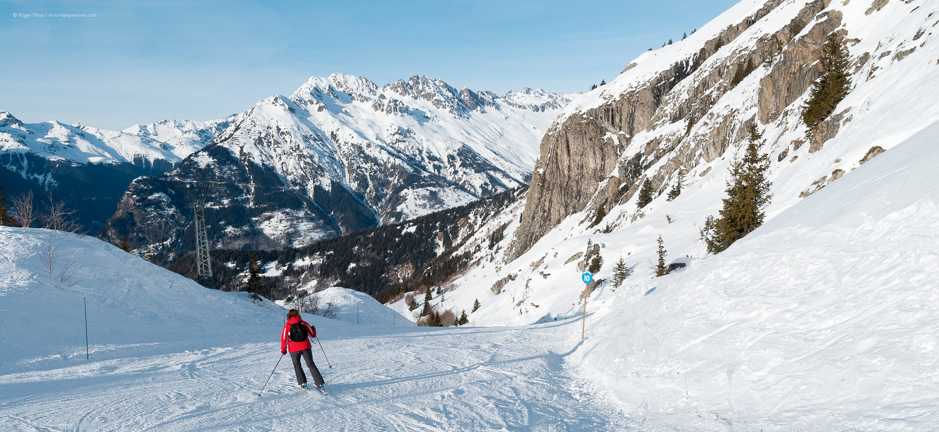 Skier descending piste between rocky outcrops