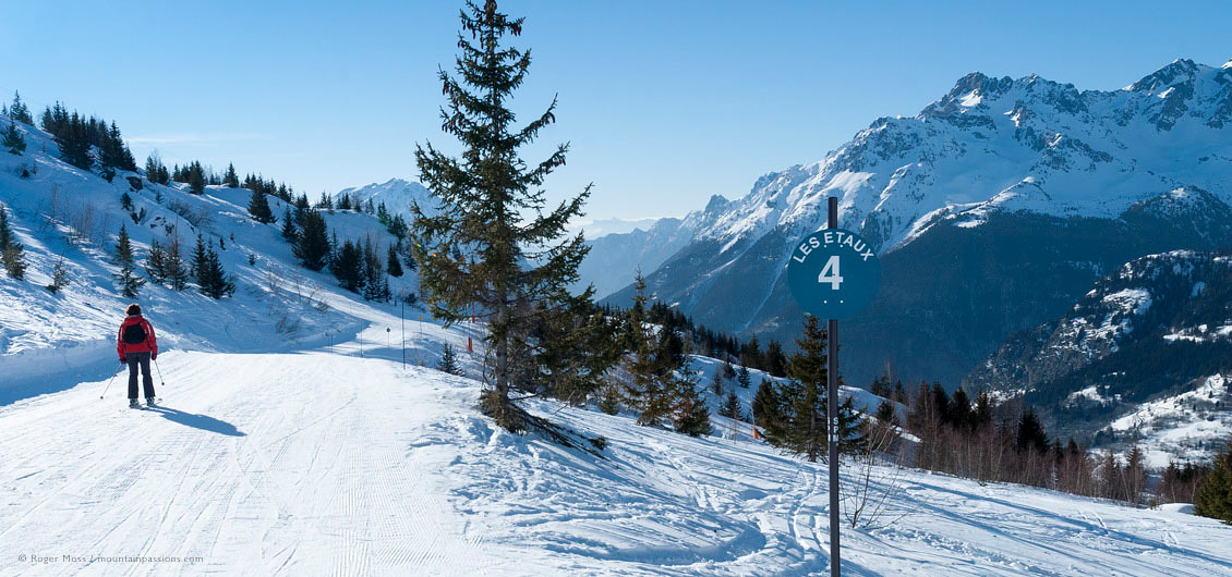 Wide view of lone skier on piste with valley views