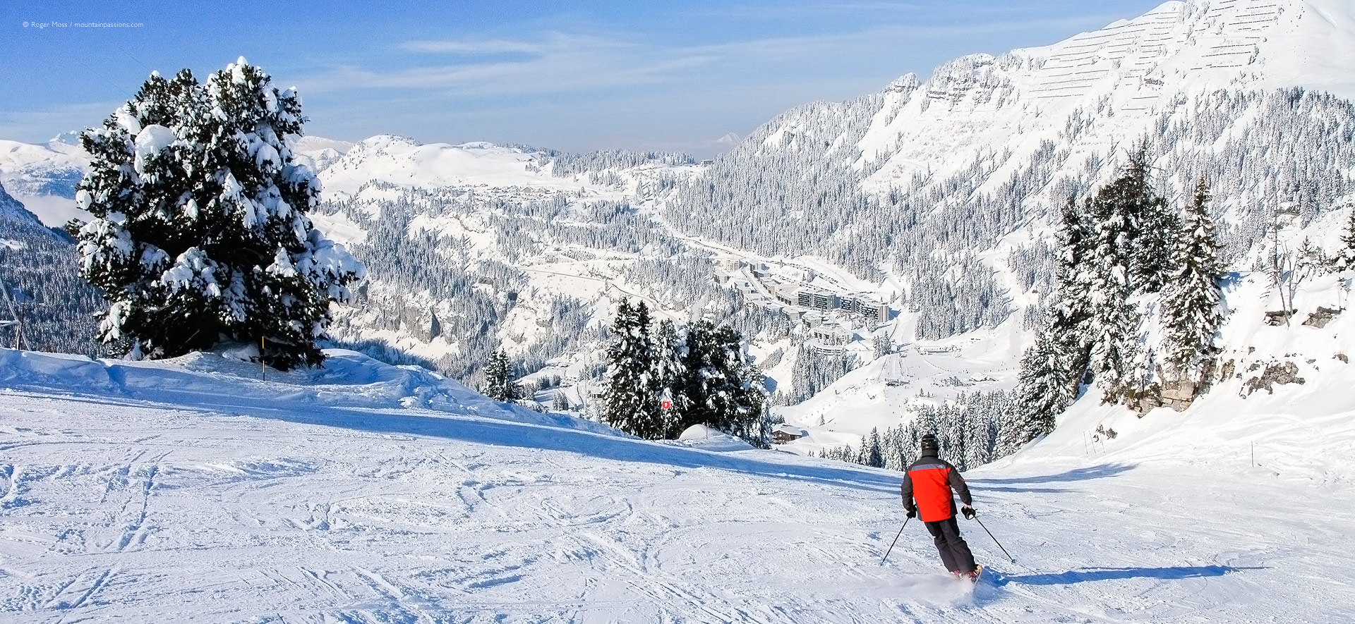 Rear view of skier on return piste with Flaine la Foret some distance ahead.