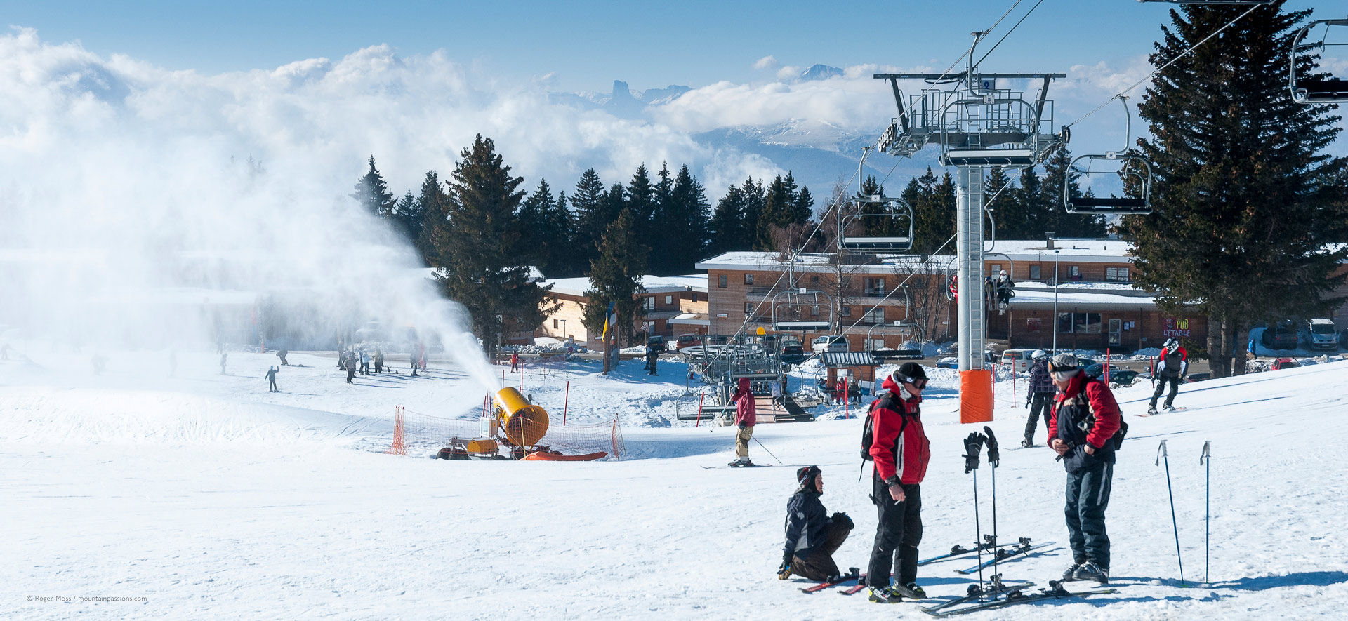 Skiers with snow-making above the ski village of Chamrousse.