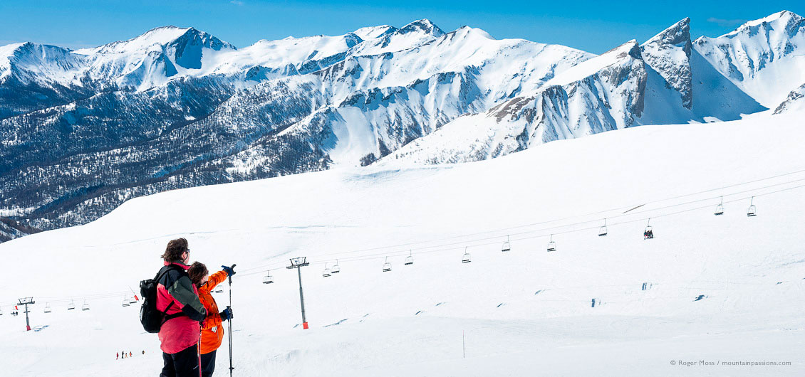 Wide view of two skiers admiring mountain scenery