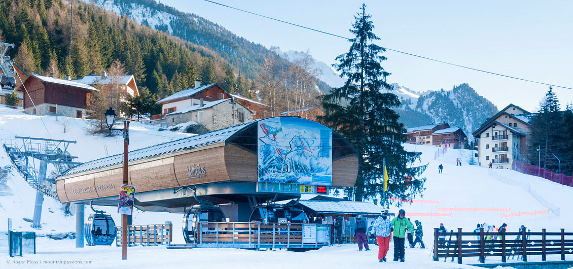 Skiers beside high-speed gondola lift, showing pistes and mountainside