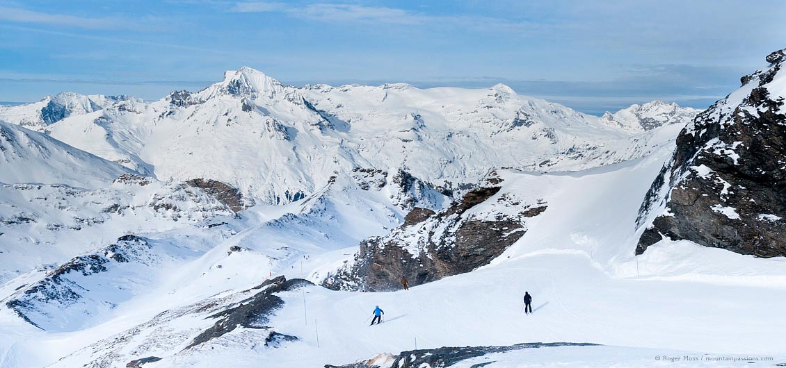 Wide view of two skiers descending high piste